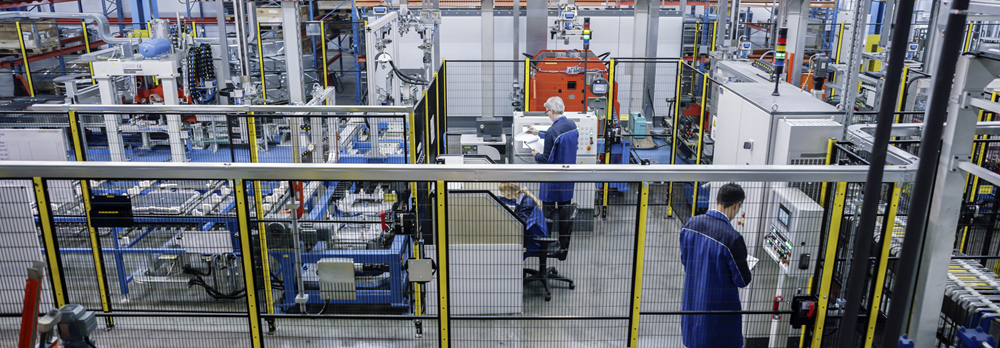 Operators in a factory with machinery guarding around the equipment.