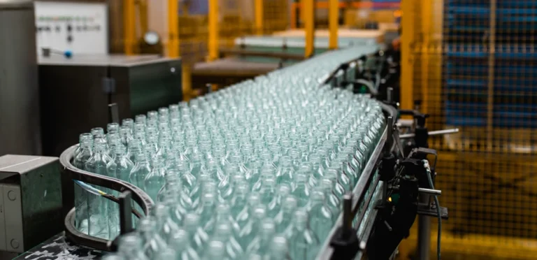 Glass bottles on conveyor at UK glass packaging production line